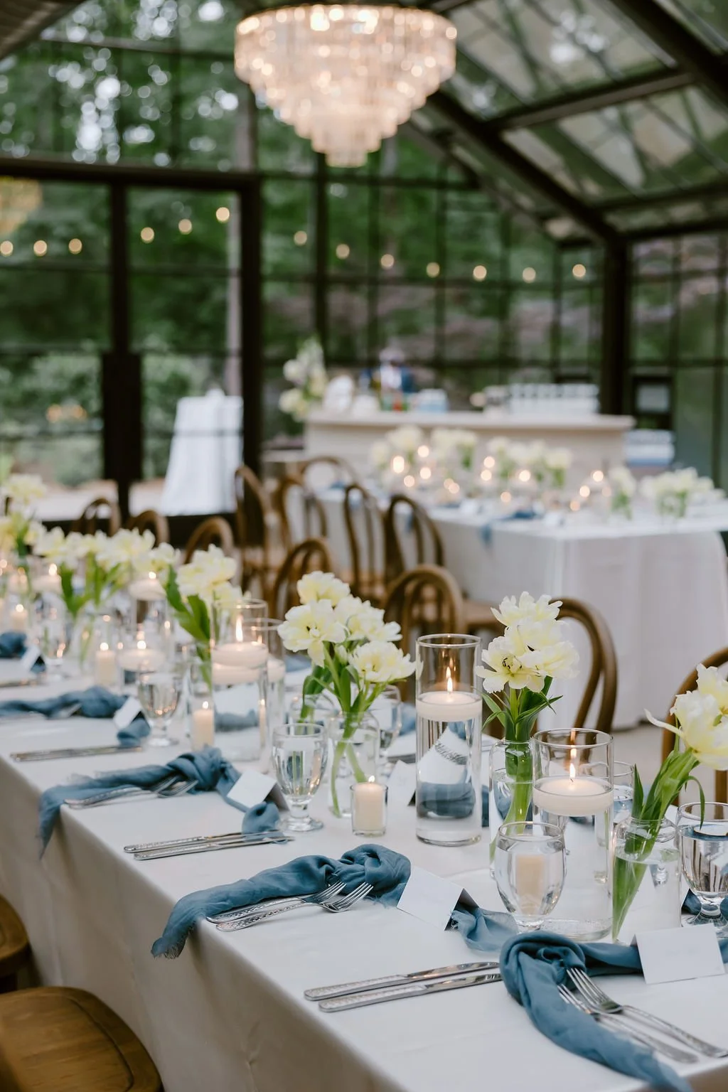 Greenhouse reception with candlelit tables and dusty-blue napkins