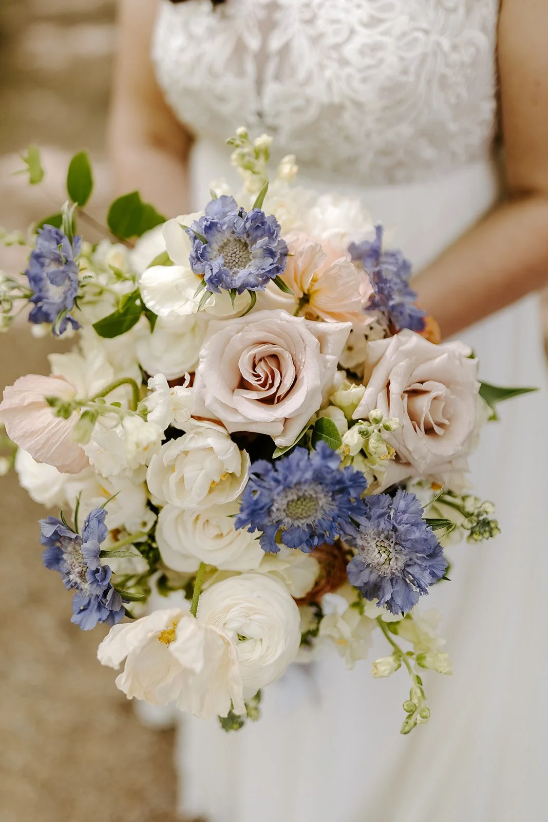 Bridal bouquet of blush roses, ranunculus and blue delphinium